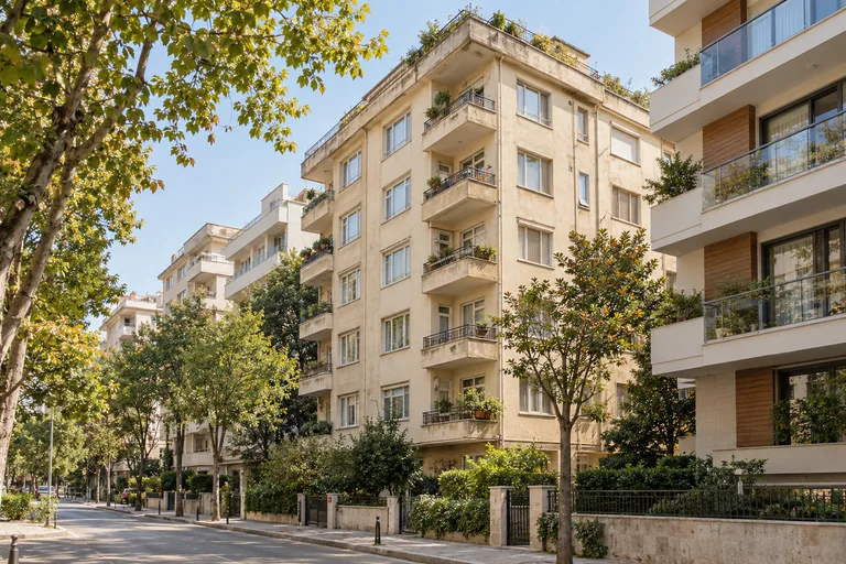 Ağaçlarla çevrili bir sokaktaki apartman yapıları
